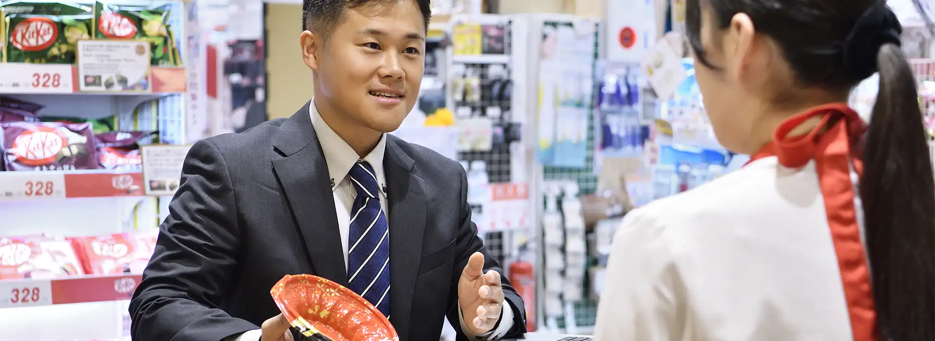 ドラッグストアで販売する惣菜のパッケージについて提案を行う社員