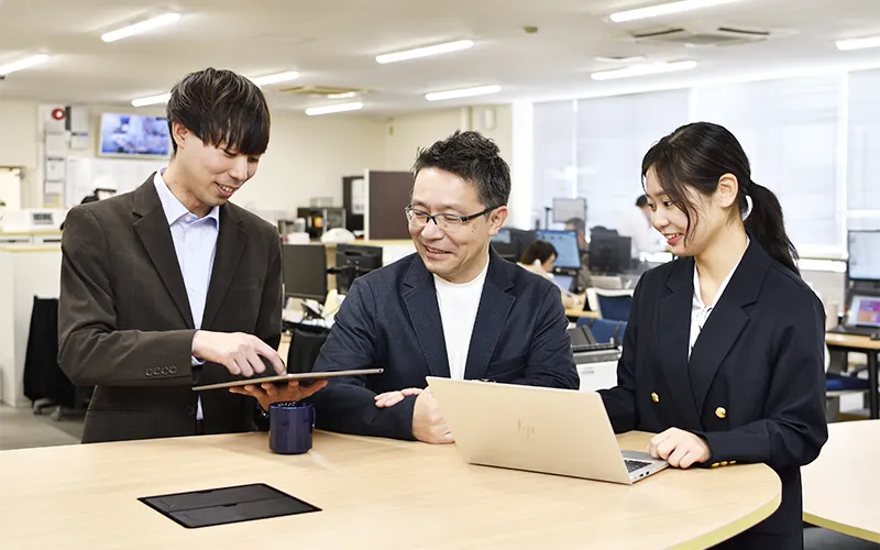 社内で打ち合わせをする三人の社員